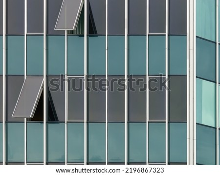Close-up photo of an exterior of a modern building with two open windows
