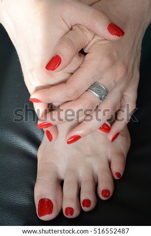 Closeup photo of a female feet and hands with beautiful red pedicure and manicure, red nails polish made in a beauty salon, all natural