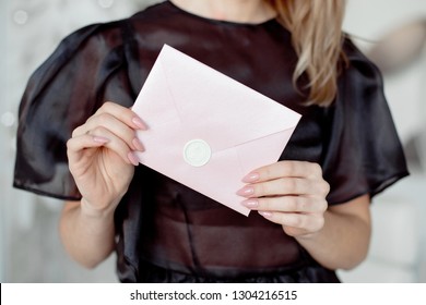 Close-up Photo Of A Female Hands Holding A Pink Invitation Envelope With A Wax Seal, A Gift Certificate, A Card, A Wedding Invitation Card