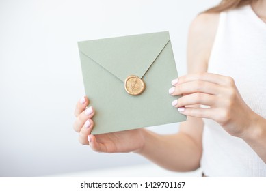 Close-up Photo Of Female Hands Holding A Silver Blue Or Pink Invitation Envelope With A Wax Seal, A Gift Certificate, A Postcard, A Wedding Invitation Card