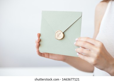 Close-up Photo Of Female Hands Holding Invitation Envelope With A Gold Wax Seal, A Gift Certificate, A Postcard, Wedding Invitation Card.