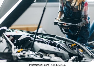 closeup photo. female mechanic holding a scanner while standing behind the hood. close up cropped photo - Powered by Shutterstock