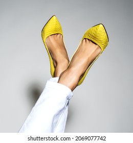 Closeup photo of female style leather bag. Part of women legs in beautiful fashionable yellow high heels.