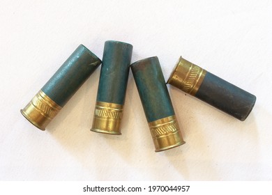 A closeup photo of four green paper type 12 gauge shotgun shells 