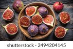 A close-up photo of fresh figs, some whole and some halved, displayed in a wooden bowl on a rustic table.