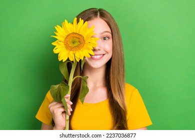 Closeup photo of funky cute schoolgirl teen age toothy beaming smile hold yellow blossom sun flower enjoy summer isolated on green color background - Powered by Shutterstock