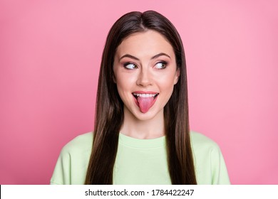 Closeup photo of funny attractive lady long hairdo funny girlish stick tongue mouth playful mood look side empty space wear casual green sweatshirt pullover isolated pink color background
