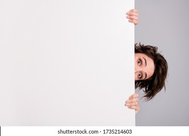 Closeup photo of funny pretty lady holding hands empty paper poster proposing advert place look interested peeking eyes tricky crazy person isolated grey color background - Shutterstock ID 1735214603