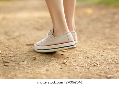 Close-up Photo Of Girl's Legs In White Converse On Ground Background