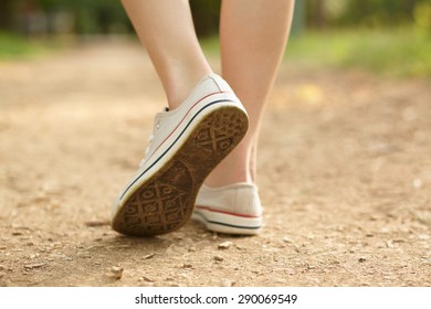 Close-up Photo Of Girl's Legs In White Converse On Ground Background