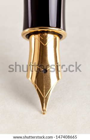 Close-up photo of a gold nib fountain pen on expensive paper.