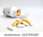 Closeup photo of group of yellow and white color pills against medicine bottle background on isolated white background