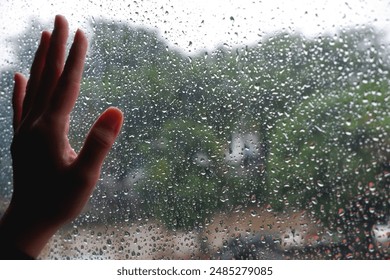 Close-up photo of hand on window with raindrops, showing soft touch and detailed water droplets. Ideal for illustrations of melancholy, introspection and emotions during the rain - Powered by Shutterstock