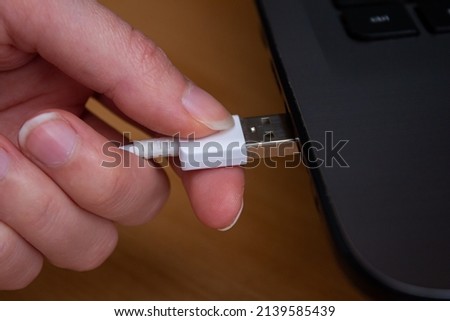 Closeup photo of hand plugging usb cable to laptop.