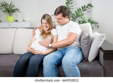 Closeup photo of happy couple expecting baby relaxing on sofa