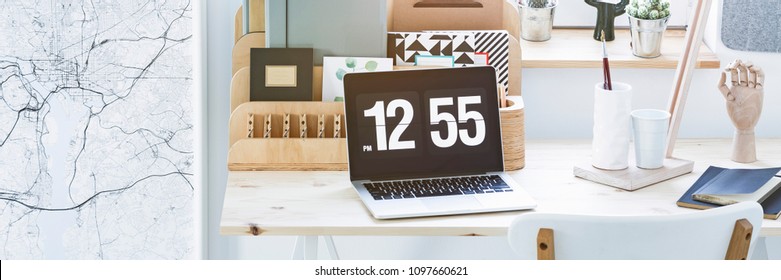 Close-up Photo Of A Laptop With Time Screensaver Placed On Home Office Wooden Desk
