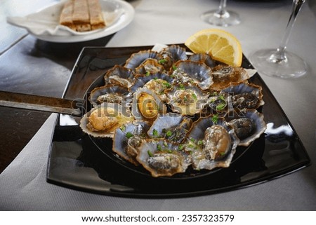 Closeup photo of limpets with butter sauce served on the hot pan with lemon on the side. Seafood. Traditional limpets, lapas from Madeira Island, Portugal. Fresh seafood. 