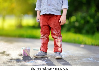 Close-up Photo Of Little Kid Boy Drawing With Colored Chalk On Asphalt. Creative Leisure For Toddler Child In Summer Park. Street Art, Kids Education. Dirty Clothes.