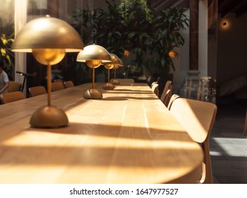 Closeup photo of long wooden table and metal lamos in modern library