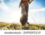 Close-up photo of male legs in trekking boots walking on a hiking trail - Happy hiker climbing mountains - Travel and sport life style concept 