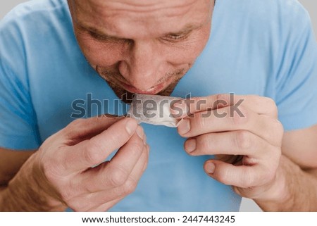 Closeup photo of man with flu infection suffering from anosmia trying to smell teabag. Fragrant reminiscence: Man reflects on loss, stirred by a smell [[stock_photo]] © 