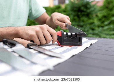 Close-up photo of man sharpening knives with special knife sharpener outdoor - Powered by Shutterstock