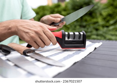 Close-up photo of man sharpening knives with special knife sharpener outdoor - Powered by Shutterstock