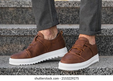 Close-up photo of men's leather brown sneakers. Genuine leather shoes with white soles.