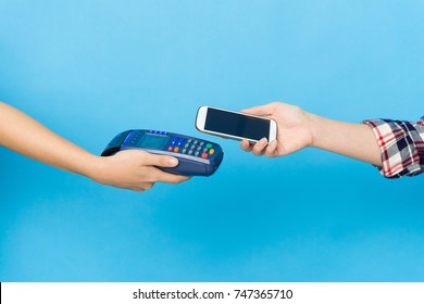 closeup photo of mobile pay with credit card machine and cell smart phone isolated on blue background.