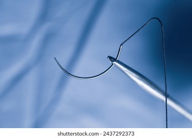 Closeup photo of a needle holder and half circle needle with suture during operation. - Powered by Shutterstock