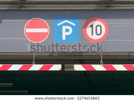 Close-up photo of a no entry, parking, and speed limit ten traffic signs at the top of the entrance to the underground garage