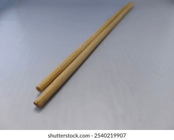 Close-up photo of a pair of chopsticks on a white background, emphasizing their elegant design and natural texture, ideal for culinary and dining-themed projects. - Powered by Shutterstock