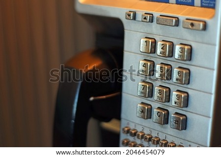 A close-up photo of pay phone in a phone booth.