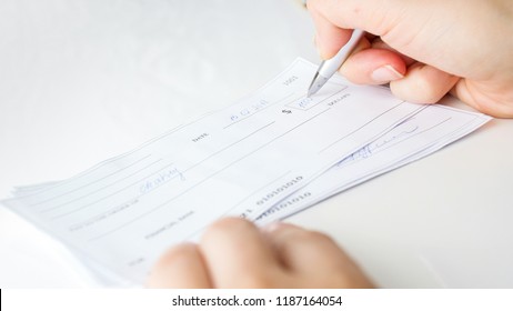 Closeup Photo Of Person Writing Bank Cheque For Charity Purposes