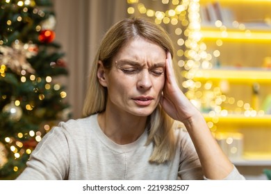 Close-up Photo Portrait Of Mature Woman Lonely And Depressed On Christmas, Thinking Wife Sitting On Sofa Near Christmas Tree In Living Room, On New Year Holidays Alone.