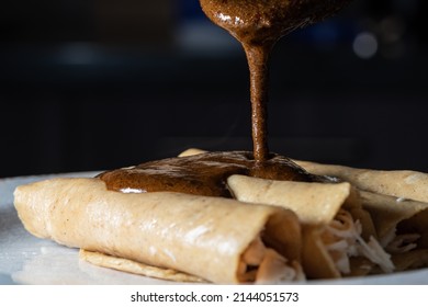 Closeup Photo Of The Preparation Of Typical Mexican Food. Mole Enchiladas. Fried Tortillas With Chicken Inside And Mole Sauce On Top.