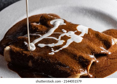 Closeup Photo Of The Preparation Of Typical Mexican Food. Mole Enchiladas. Fried Tortillas With Chicken Inside And Mole Sauce On Top.