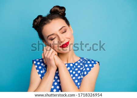 Closeup photo of pretty charming lady red pomade eyes closed hold hands near face overjoyed relaxed wear dotted white retro blouse shirt isolated blue color background