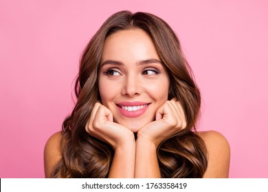 Closeup photo of pretty funny curly lady overjoyed facial expression arms on cheeks look side empty space dreamer wear white casual singlet isolated bright pink color background