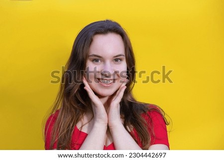 Closeup photo of pretty happy lady wear red dress and looking empty space. isolated yellow color background. Young emotional girl concept. Copy space