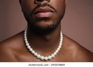 Close-up Photo Of Shirtless Black Man With Pearl Necklace Over Beige Background.