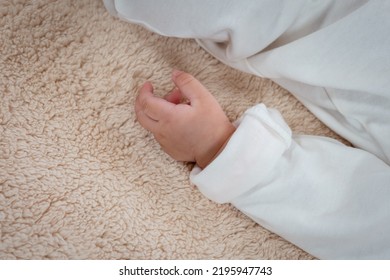 Close-up Photo Of A Small Hand Of A 3-month-old Asian Newborn, Left Hand, Resting Against A Little Girl's Body. Sleep On A Soft Bed In The Bedroom Looks Relaxed.