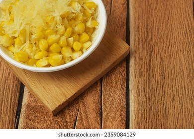 Closeup photo of some shaved corn sprinkled with sweet cheese and milk sitting on a wooden table