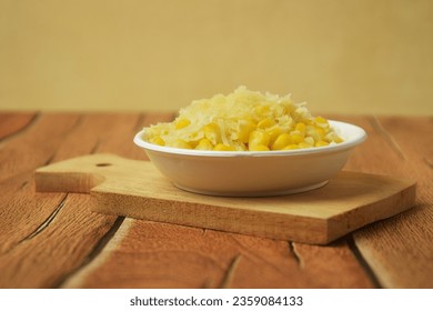 Closeup photo of some shaved corn sprinkled with sweet cheese and milk sitting on a wooden table