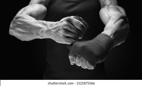 Close-up photo of strong man wrap hands on black background Man is wrapping hands with boxing wraps Strong hands and fist, ready for training and active exercise Bodybuilder fitness lifestyle concept - Shutterstock ID 1521875366