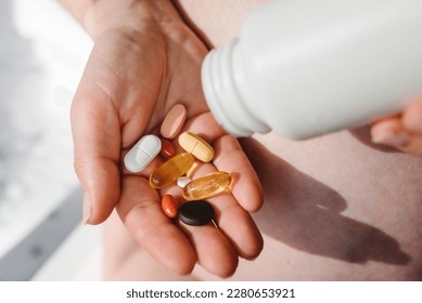 Closeup photo of supplements with a white bottle. Pregnant woman take omega 3, multivitamins, vitamins B, C, D, collagen tablets, probiotics, iron capsule. Girl hold vitamins daily. Top view.