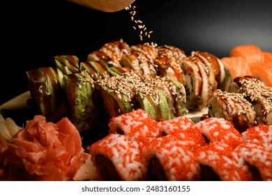 Close-up photo of sushi rolls green dragon with avocado and seared philadelphia with tuna sprinkled with sesame seeds on a wooden board, also rolls with caviar and salmon lie nearby - Powered by Shutterstock