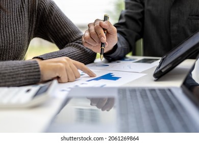 Close-up photo of two businessmen pointing at a sales data sheet in graph format, they are meeting together on the topic of managing sales growth. Concept of business cooperation and sales management.