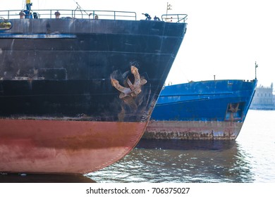 Closeup Photo Of Two Couple Fishing Boat Keel Half Way Up A Launch Rail In Marina For Repairs Or Maintenance. Rusty Anchor. Old Rusty Anchor Waiting To Start. Broken Rusty Ship Standing On River Bank