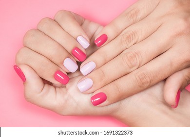 Closeup photo of two female hands and fingers manicured. Fingernails with fresh professional spring or summer naildesign isolated on pastel pink background. Painted nails with modern gel-polish.